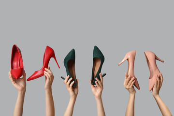 Female hands with different stylish high heels on grey background