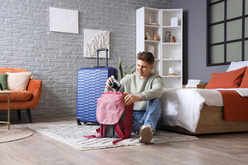 Male tourist taking photo camera from backpack in hotel room