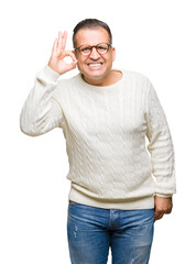 Fototapeta premium Middle age arab man wearing glasses over isolated background smiling positive doing ok sign with hand and fingers. Successful expression.