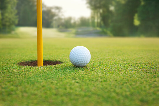 Close up of golf ball on a green near hole with pin