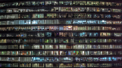 Working evening in glass office building with numerous offices with glass walls and windows timelapse