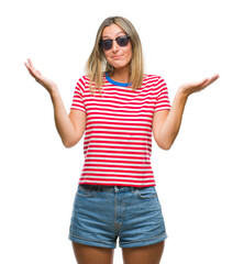 Young beautiful woman wearing sunglasses over isolated background clueless and confused expression...