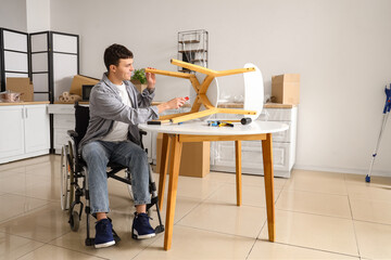 Young man in wheelchair repairing chair at home