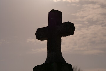 silhouette of a concrete cross on the background of the sky at sunset