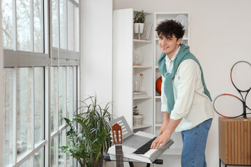 Male student playing synthesizer at home