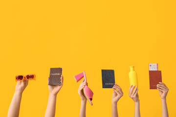 Female hands with sunglasses, passports, sunscreen and heeled sandals on yellow background. Travel...