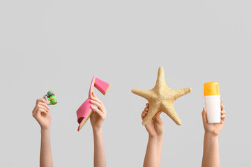 Female hands with starfish, heeled sandals, lock and sunscreen on grey background. Travel concept.