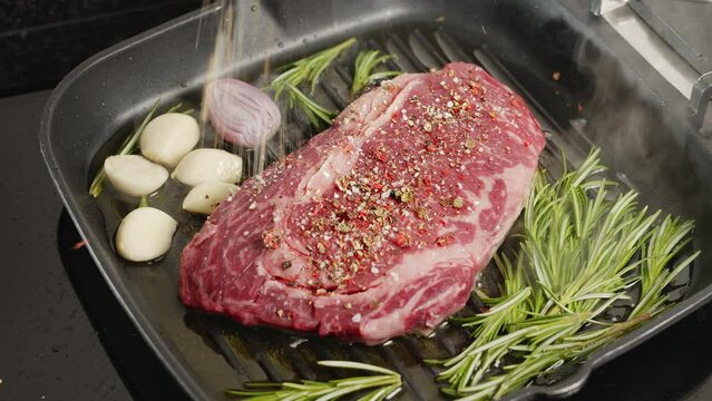 Ribeye steak with herbs and garlic are being roasted on the grill pan. 