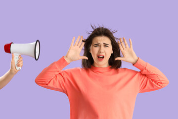 Beautiful young stressed woman screaming and hand with megaphone on purple background. Stress Awareness Month - obrazy, fototapety, plakaty