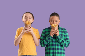 Happy cute little children with french fries on purple background