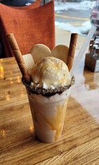 Milkshake with cookies on top, covered in chocolate, sitting on a table, food photography.