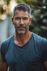 Fototapeta premium Handsome mature man with a confident gaze against a backdrop of lush plants
