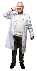 Handsome senior doctor man wearing medical coat Pointing with hand finger to face and nose, smiling cheerful