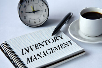 INVENTORY MANAGEMENT - words in a notebook on a white background with a clock and a cup of coffee
