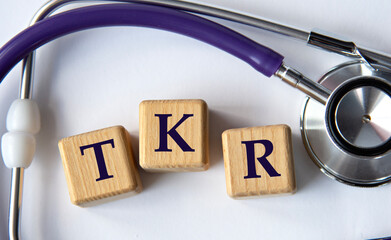 Cubes with the abbreviation TKR on the background of a stethoscope.