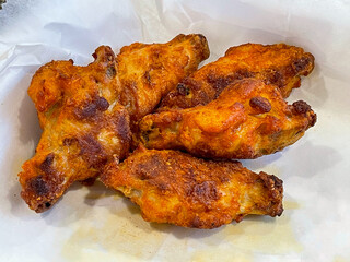 Five fried chicken wings in a basket with white waxed paper