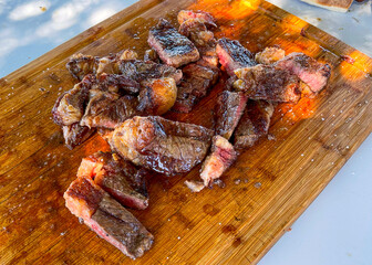 Grilled ribeye steak sliced on a wooden cutting board with kosher salt