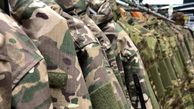 Camouflage military uniforms displayed in assorted colors and patterns on racks within a store