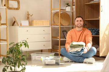 Young man with stack of charity clothes sitting at home