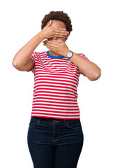 Beautiful young african american woman wearing glasses over isolated background Covering eyes and mouth with hands, surprised and shocked. Hiding emotion