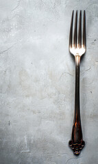 Single silver fork on a textured grey background with minimalist style.