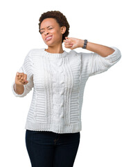 Beautiful young african american woman wearing sweater over isolated background stretching back,...