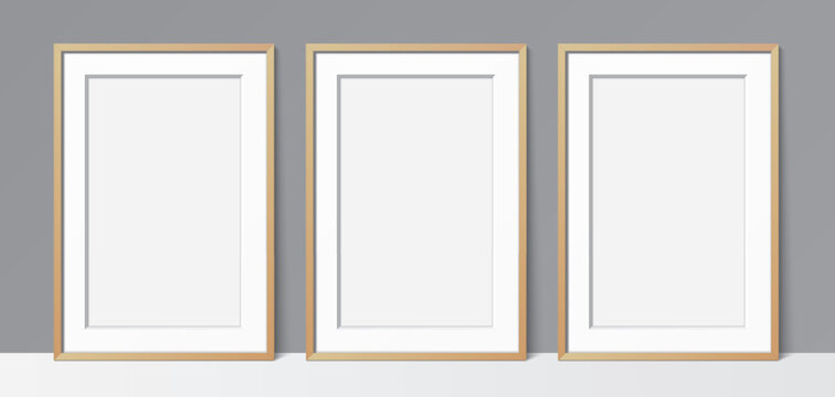 3 Blanck poster wooden frames leaning against a grey wall background. Poster gallery vector mockup for art, image, or text placement.