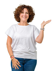 Beautiful middle ager senior woman wearing white t-shirt over isolated background smiling cheerful presenting and pointing with palm of hand looking at the camera.