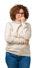 Beautiful middle ager senior woman wearing turtleneck sweater and glasses over isolated background looking stressed and nervous with hands on mouth biting nails. Anxiety problem.