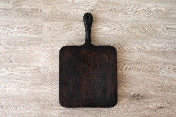 Empty dark brown wooden board on beige table, flat lay, natural kitchen beverage for food product...