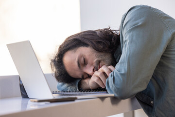homme qui dort au bureau devant son ordinateur portable. Symbole du stress, de la fatigue et du surmenage au travail