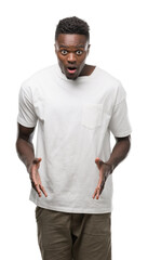 Young african american man wearing white t-shirt afraid and shocked with surprise expression, fear and excited face.