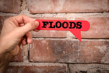 FLOODS. Red speech bubble with text on a red brick background - 781603873