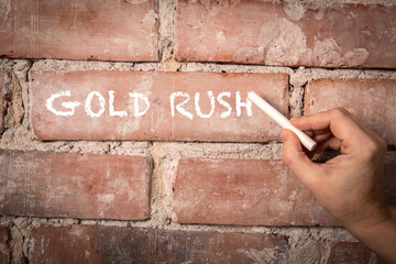 Gold Rush. Text written with white chalk on a red brick background - 781604090