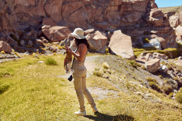 side view female traveler taking photos with her cell phone in a ravine's landscape in San Pedro de Atacama