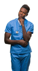 Young african american doctor man over isolated background wearing surgeon uniform with hand on chin thinking about question, pensive expression. Smiling with thoughtful face. Doubt concept.