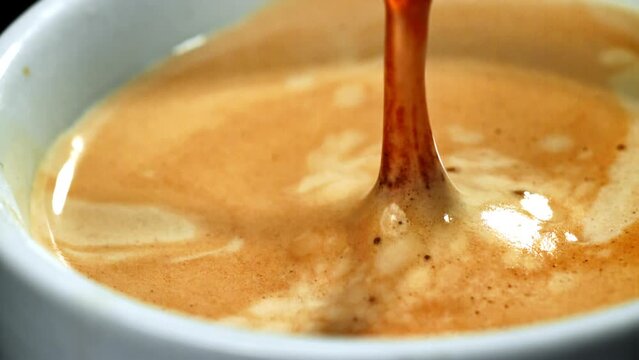 A visually appealing video showcasing the preparation of coffee, with shots of pouring and drops falling into a cup, creating an enticing scene