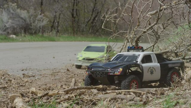 RC cars racing past police RC car - low, steady cam shot