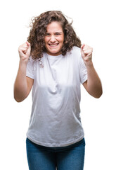 Beautiful brunette curly hair young girl wearing casual t-shirt over isolated background excited for success with arms raised celebrating victory smiling. Winner concept.