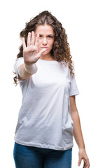 Beautiful brunette curly hair young girl wearing casual t-shirt over isolated background doing stop...