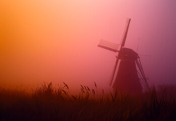 Windmill in the mist. A windmill rises from a misty field - obrazy, fototapety, plakaty