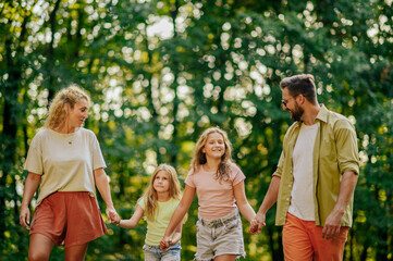 A loving family is talking a walk in forest.