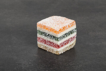 Vegan Multi-layered multicolored jelly marmalade of square shape. Dark gray background. Close-up