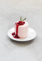 Modern dessert. Pomegranate cream pudding, Panna Cotta cylindrical shape, with Pomegranate sauce. On a plate. Light gray background