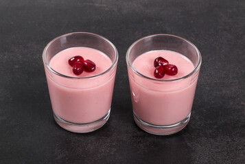 Pomegranate cream jelly, Panna Cotta in a glass. Dark background. Close-up