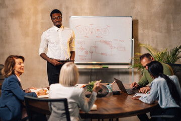 Multiracial manger presenting marketing plan on whiteboard at meeting room