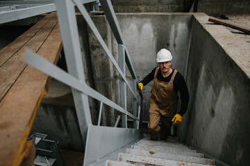 A construction engineer climbs a metal ladder at the construction site of a grain silo.