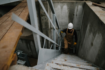 A construction engineer climbs a metal ladder at the construction site of a grain silo.
