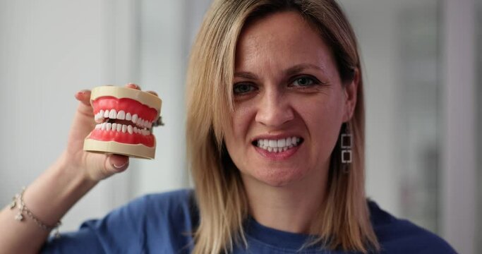 Woman smiles and holds artificial jaw concept