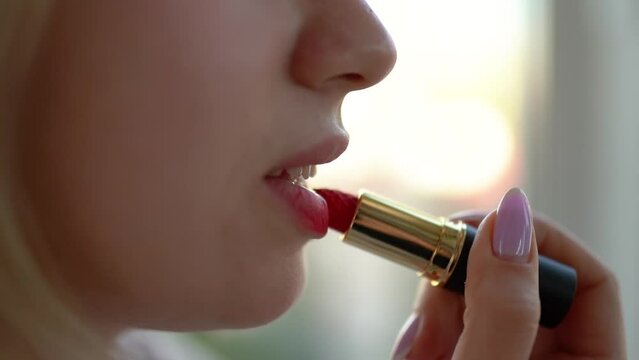 beautiful young girl paints her lips with bright red lipstick close-up, make-up and female beauty